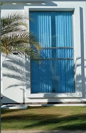 Fachada flotante en vidrio azul en una casa de dos niveles